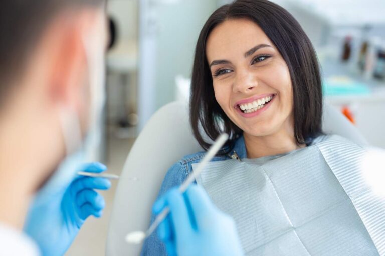 Person brushing teeth beside a bathroom sink with a soft toothbrush, toothpaste, and floss visible.